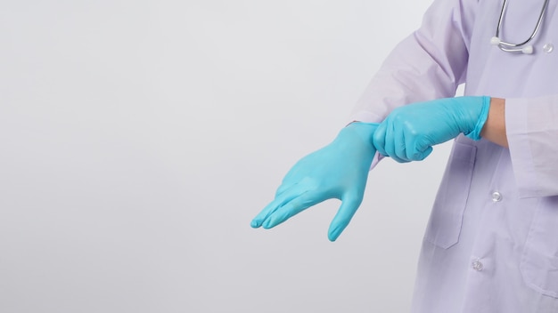 Foto la mano de los médicos está tirando guantes de látex azul sobre fondo blanco.