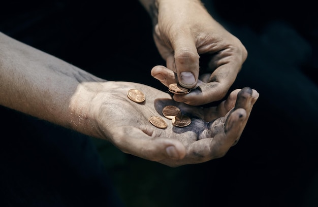 Mano de mendigo con algunas monedas pidiendo dinero (pobreza, hambre, ansiedad, concepto de quiebra)