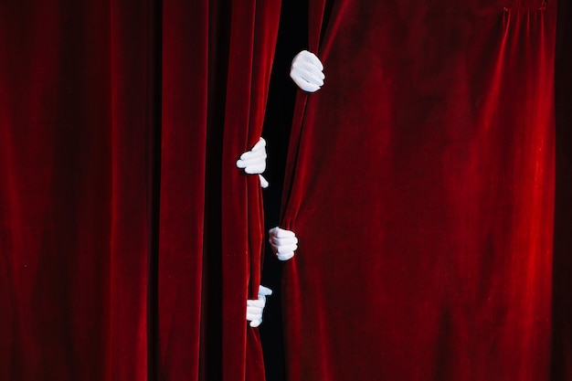 Foto la mano de mime mantiene cerrada la cortina roja