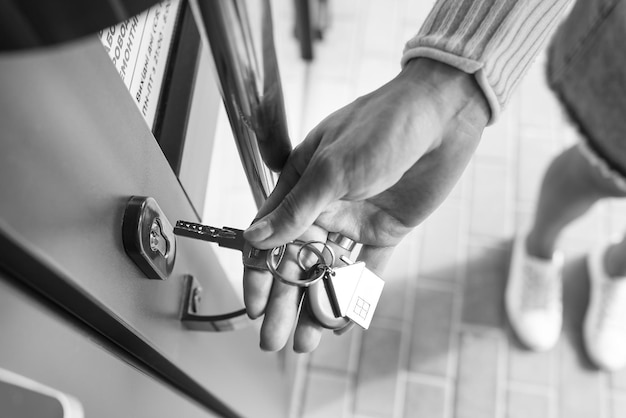 La mano de una mujer abre la puerta con una llave de la que cuelga el llavero de la casa.