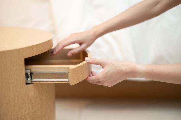 Mano de mujer abriendo un cajón en la mesa de madera.