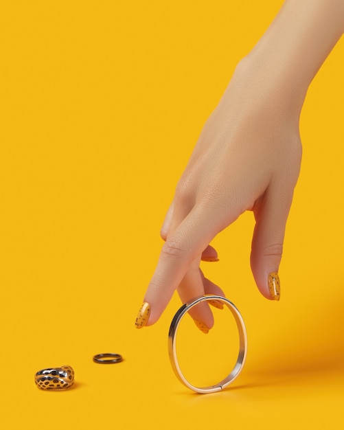 Mano de mujer con accesorios de joyería sobre fondo naranja