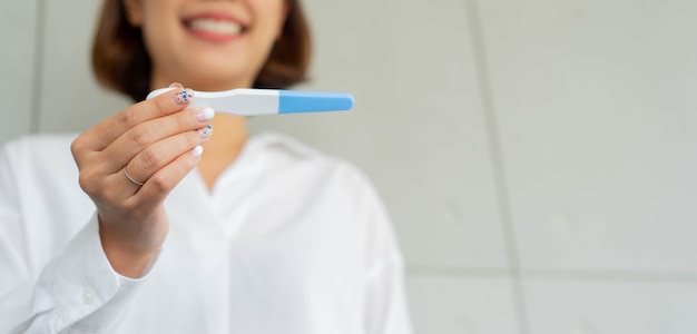 Mano de mujer adulta con kit de prueba de embarazo y resultado de espera en casa para el concepto de vida familiar