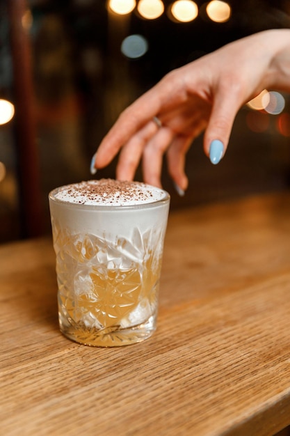 Mano de mujer alcanzando un cóctel en el bar