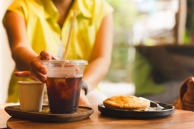 La mano de la mujer alcanzando un vaso de café en la mesa