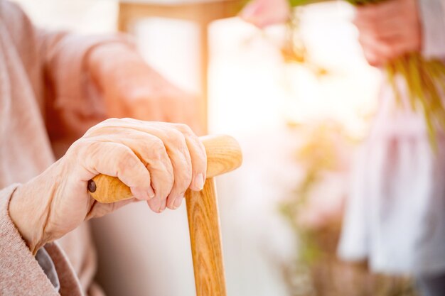 Mano de mujer anciana con bastón en luz