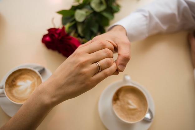 De la mano a una mujer con un anillo de bodas en la mano a un hombre en la mesa