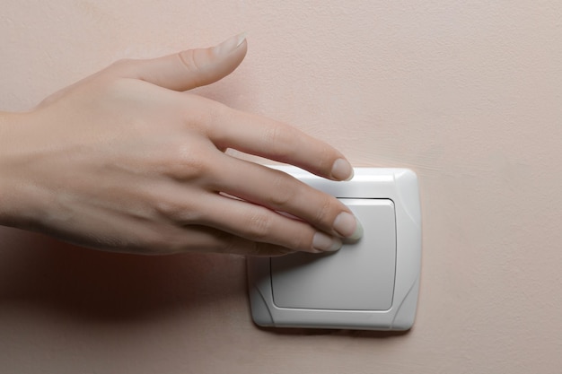 Mano de mujer apagando las luces de una habitación