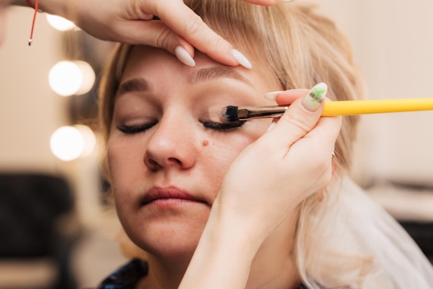 La mano de una mujer aplica sombra de ojos con un pincel de maquillaje