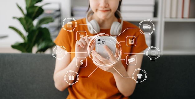 Foto la mano de la mujer asiática usando un portátil, un teléfono inteligente y una tableta y escribiendo un cuaderno en la oficina de su negocio de compras en línea en casa con icono virtual