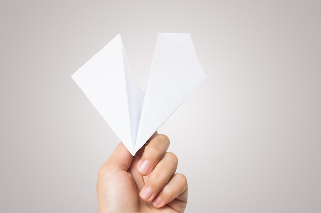 Mano de mujer Aviador de papel de dardo aislado sobre fondo blanco.