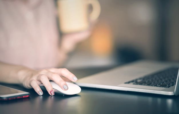 mano de mujer buscando y haga clic en el ratón usando la computadora portátil