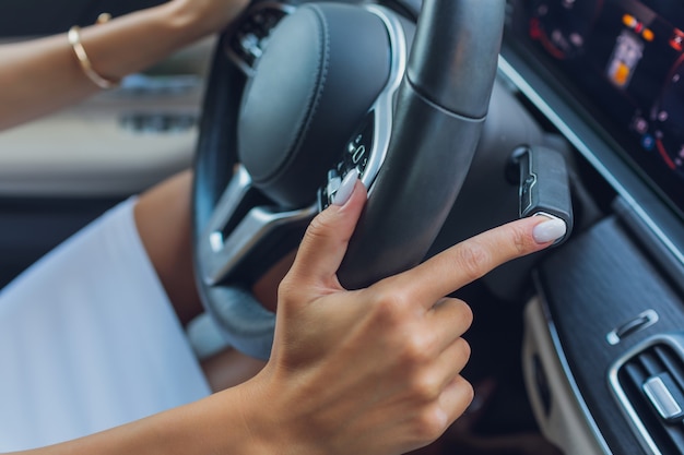 La mano de la mujer cambia los lóbulos del selector de marchas en el volante.La mano está cambiando la palanca de cambios del coche. Primer plano de una paleta de cambio de marchas manual en el volante de un coche.