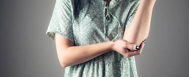 Mano de mujer en el codo de dolor