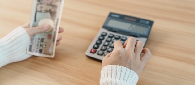 Mano de mujer contando billetes de yen japonés con calculadora Dinero de mil yenes Dinero en efectivo de Japón Recesión fiscal Economía Inflación Inversión finanzas ahorros salarios y conceptos de pago