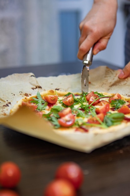 Foto mano de mujer cortando pizza en trozos