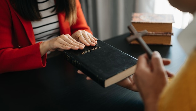 Mano de mujer con cruz Concepto de esperanza fe cristianismo religión iglesia y orar a Dios en la mesa negraxAxA