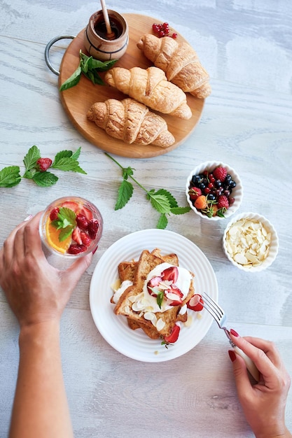 Mano de mujer desayunando tostadas francesas con fresas