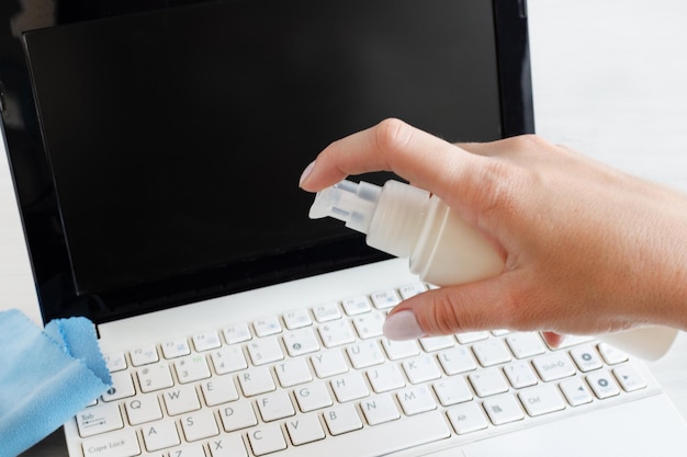 Foto mano de mujer desinfectando el teclado de la computadora con un limpiador antibacteriano