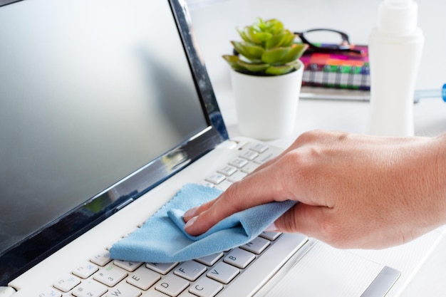 Mano de mujer desinfectando el teclado de la computadora con un paño antibacteriano