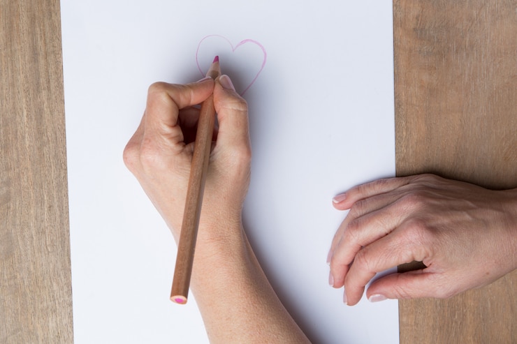 Foto mano de una mujer dibujando un corazón rosa