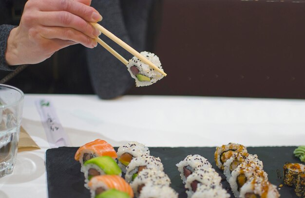 Mano de mujer eligiendo una pieza de sushi en un restaurante