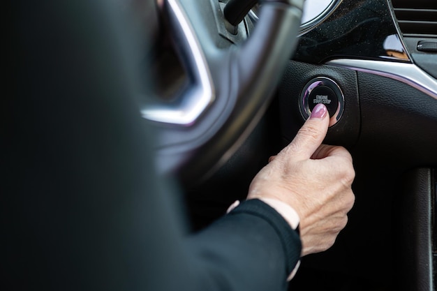 Mano de mujer empujando el botón de inicio y parada del motor del automóvil Primer plano interior del automóvil moderno