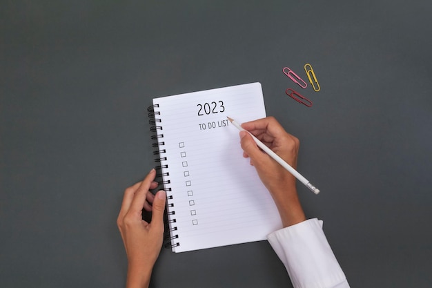 Mano de mujer escribiendo metas para 2023 en el plan del cuaderno