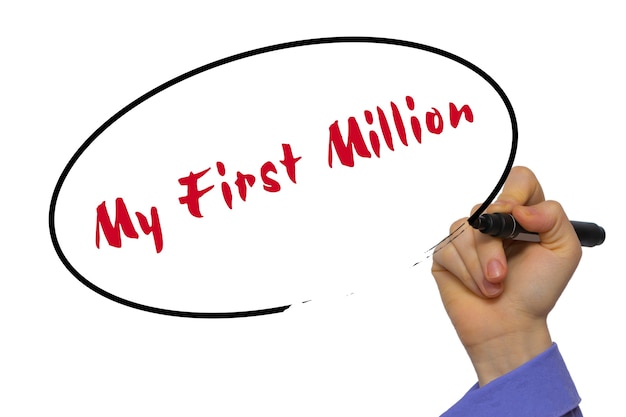 Mano de mujer escribiendo mi primer millón en tablero transparente en blanco con un marcador aislado sobre fondo blanco. Concepto de negocio. Foto de stock