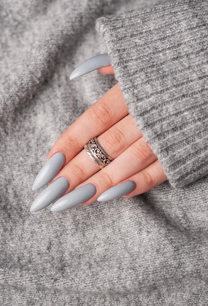 La mano de la mujer con esmalte de uñas gris