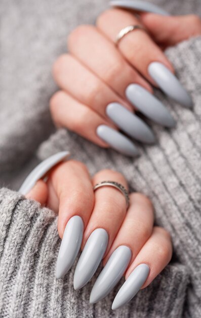 La mano de la mujer con esmalte de uñas gris