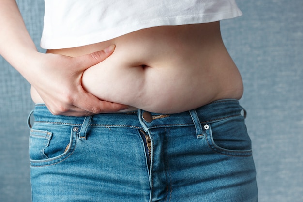 Mano de mujer con exceso de grasa abdominal, concepto de sobrepeso