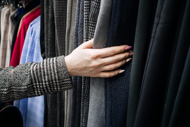 Mano de mujer en el fondo de una colección de ropa en la tienda.