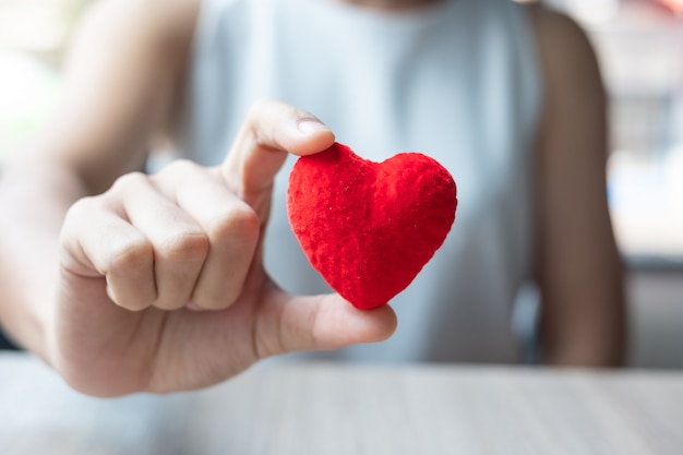 Mano de mujer con forma de corazón rojo