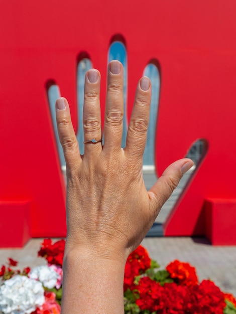 Mano de mujer frente a la decoración de la calle como pared roja con palma recortada Bakú, Azerbaiyán