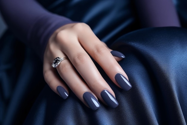 La mano de la mujer de glamour con esmalte de uñas azul marino en sus uñas Manicure de uñas marino con eskalte de gel