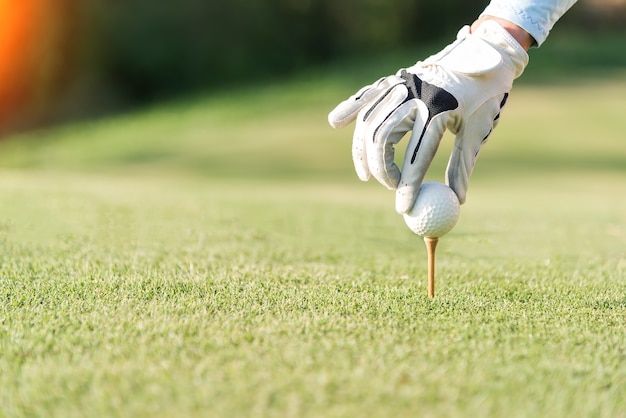 mano de mujer golf playerpush camiseta de madera con pelota de golf en el tee de hierba, para estar listo para golpear th