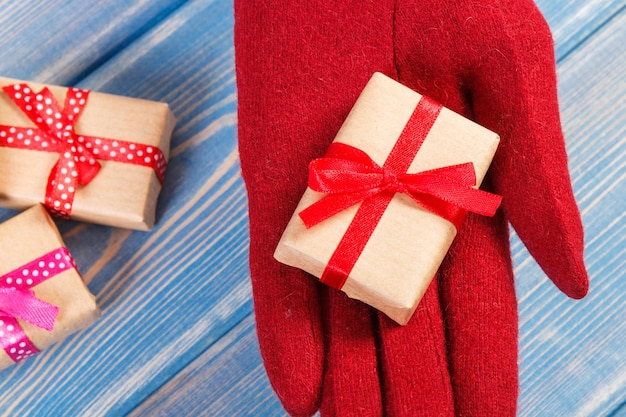 Mano de mujer en guantes con regalos para Navidad u otra celebración