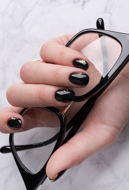 Mano de mujer hermosa con elegante manicura. Diseño minimalista de uñas negras.