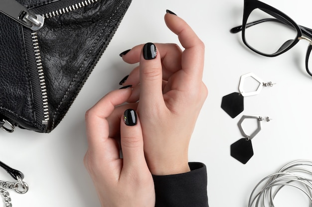 Mano de mujer hermosa con elegante manicura. Diseño minimalista de uñas negras.
