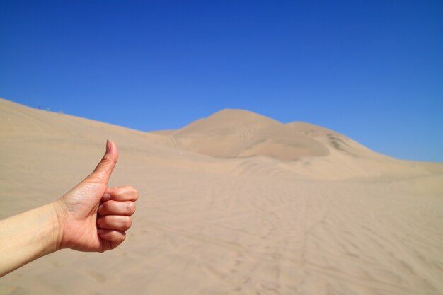 Mano de mujer hojeando la increíble vista del desierto de Huacachina en la región de Ica, Perú