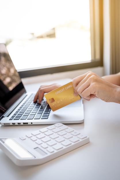 Mano de mujer joven consumidor asiático sosteniendo una tarjeta de crédito