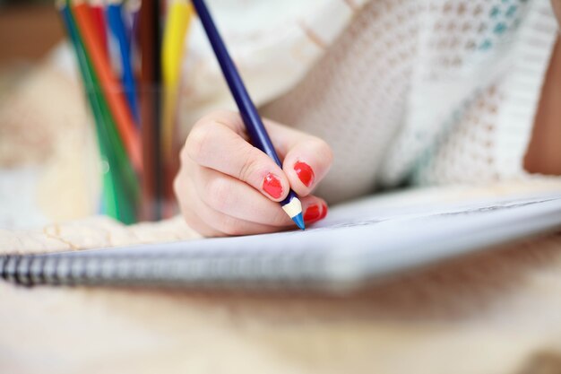 Mano de mujer joven dibujo imagen artística con crayones de colores