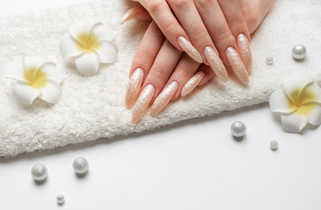 La mano de una mujer joven con manicura de perlas blancas