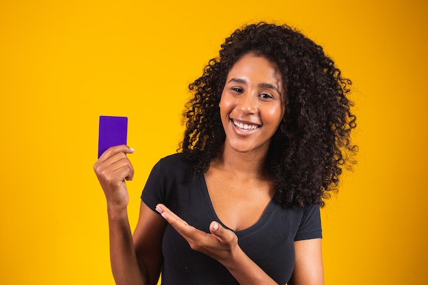 La mano de la mujer joven sostiene la maqueta de la tarjeta púrpura. Mujer sosteniendo la tarjeta de compras. Hermosa joven con tarjeta bancaria de crédito