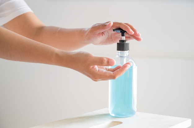 Mano de mujer lavando con gel de alcohol de la botella de la bomba.