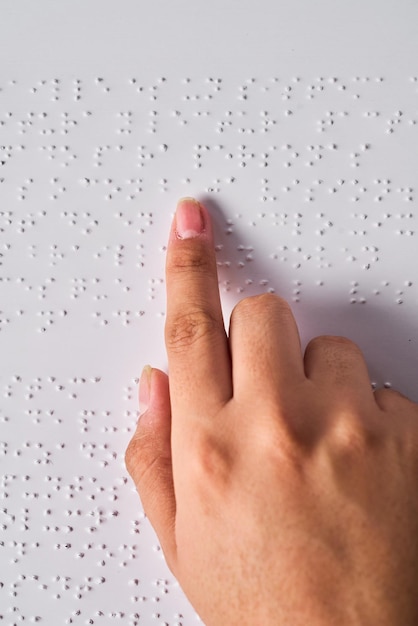 Una mano de mujer leyendo braille con fondo azul Celebración anual