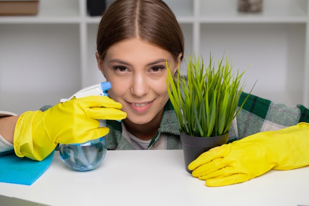 Mano de una mujer limpiando el escritorio con guantes amarillos