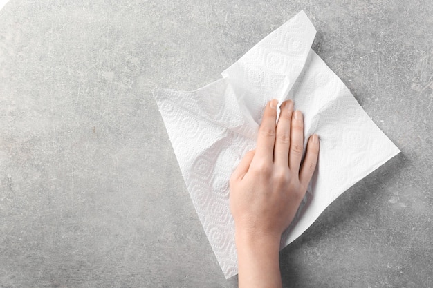 Mano de mujer limpiando la superficie clara con una toalla de papel