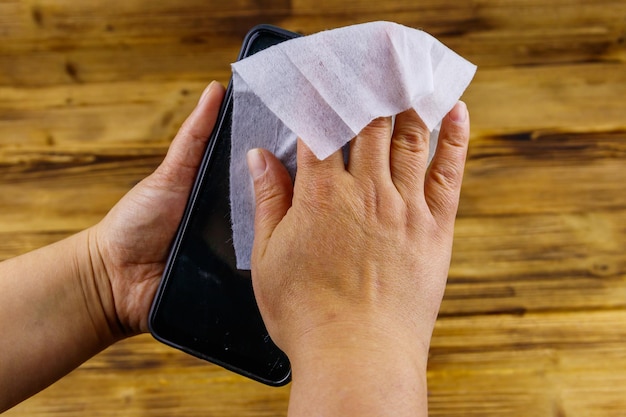 Mano de mujer limpieza de la pantalla del teléfono inteligente con una toallita húmeda